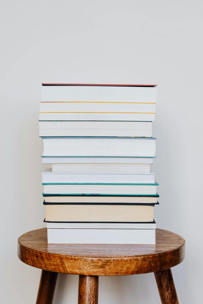 pexels-photo-4219041-4219041 A neat stack of books placed on a rustic wooden stool, perfect for reading scenes.